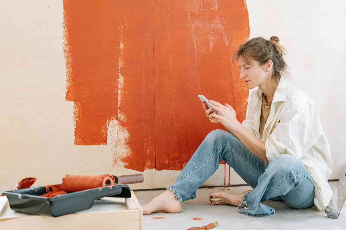 donna legge un messaggio mentre ridipinge casa