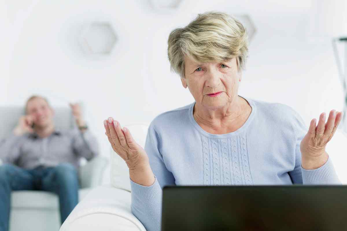 una donna anziana allarga le braccia e dietro il marito