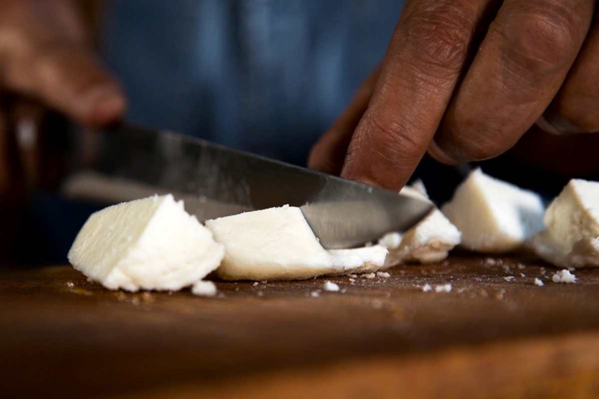 una mano taglia a pezzi il formaggio pule