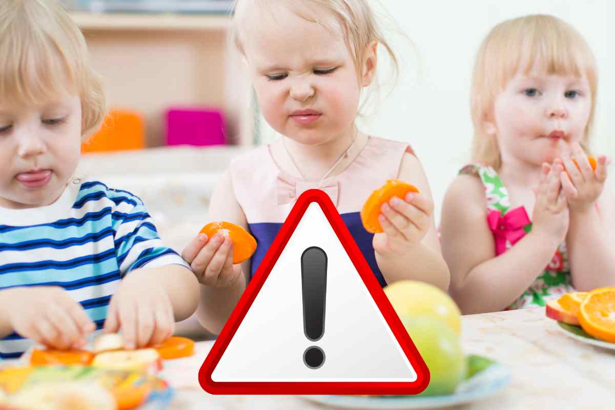 bambini mangiano frutta e davanti un segnale di pericolo