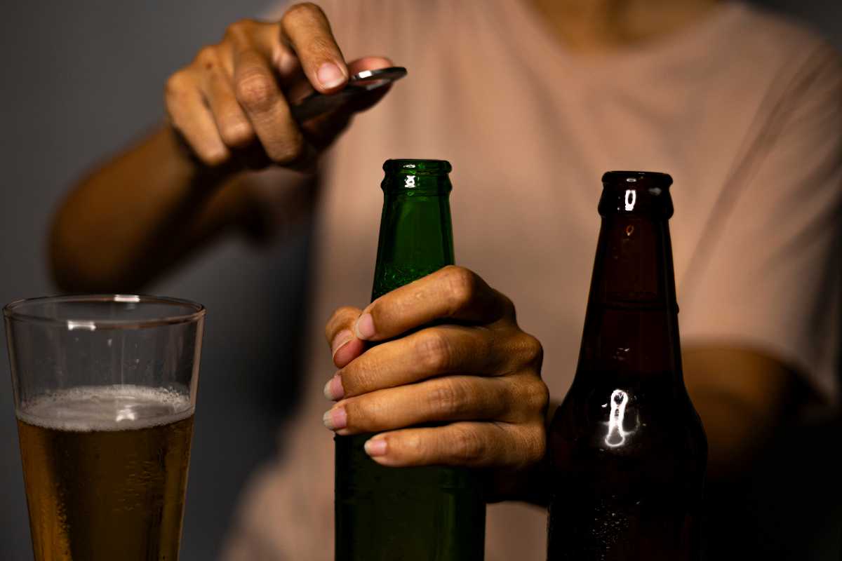 una mano stappa bottiglie di birra