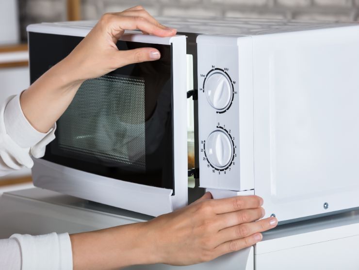 donna che chiude sportello del forno a microonde