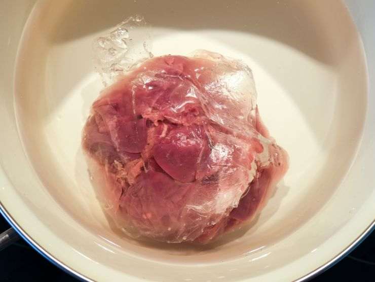 pentola piena d'acqua in cui c'è la carne che si deve scongelare