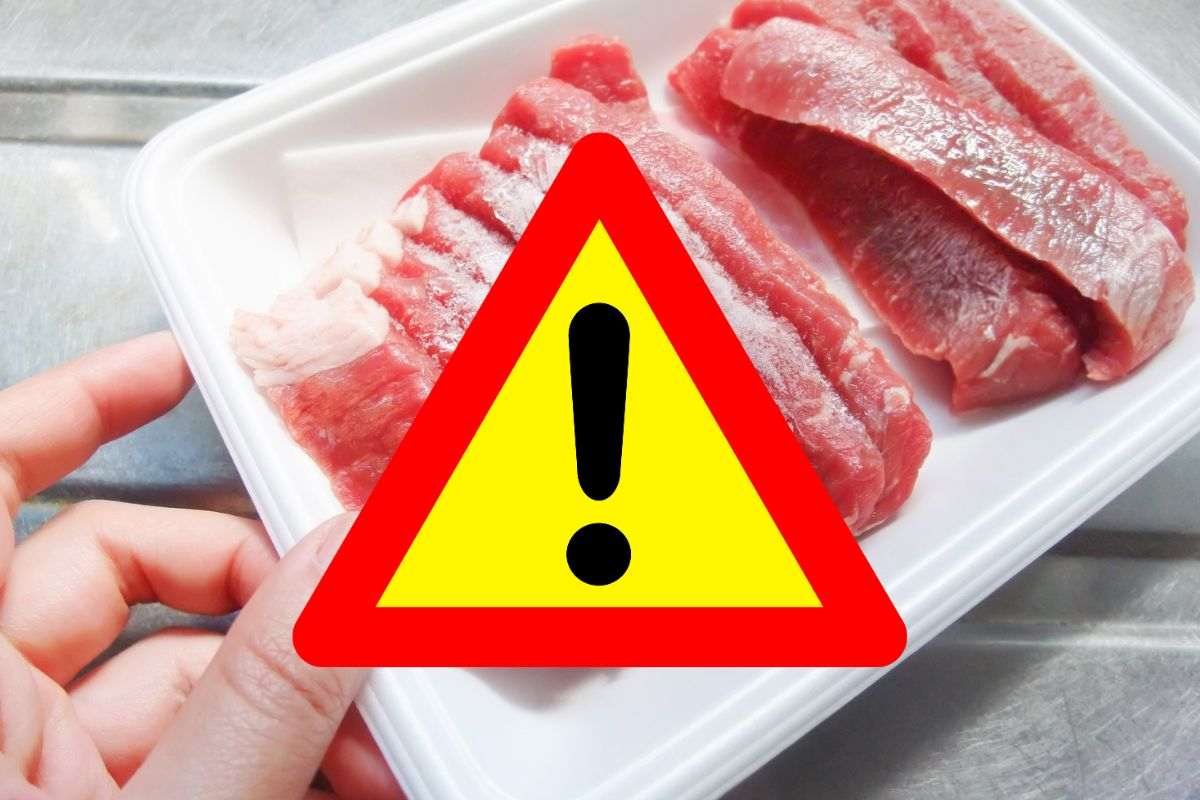 vaschetta con carne congelata e segnale di pericolo in primo piano