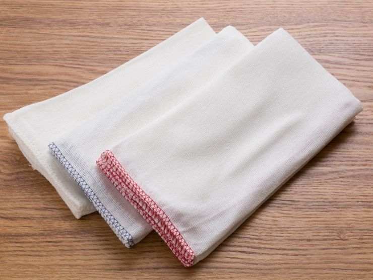tre strofinacci bianchi di stoffa piegati su un tavolo
