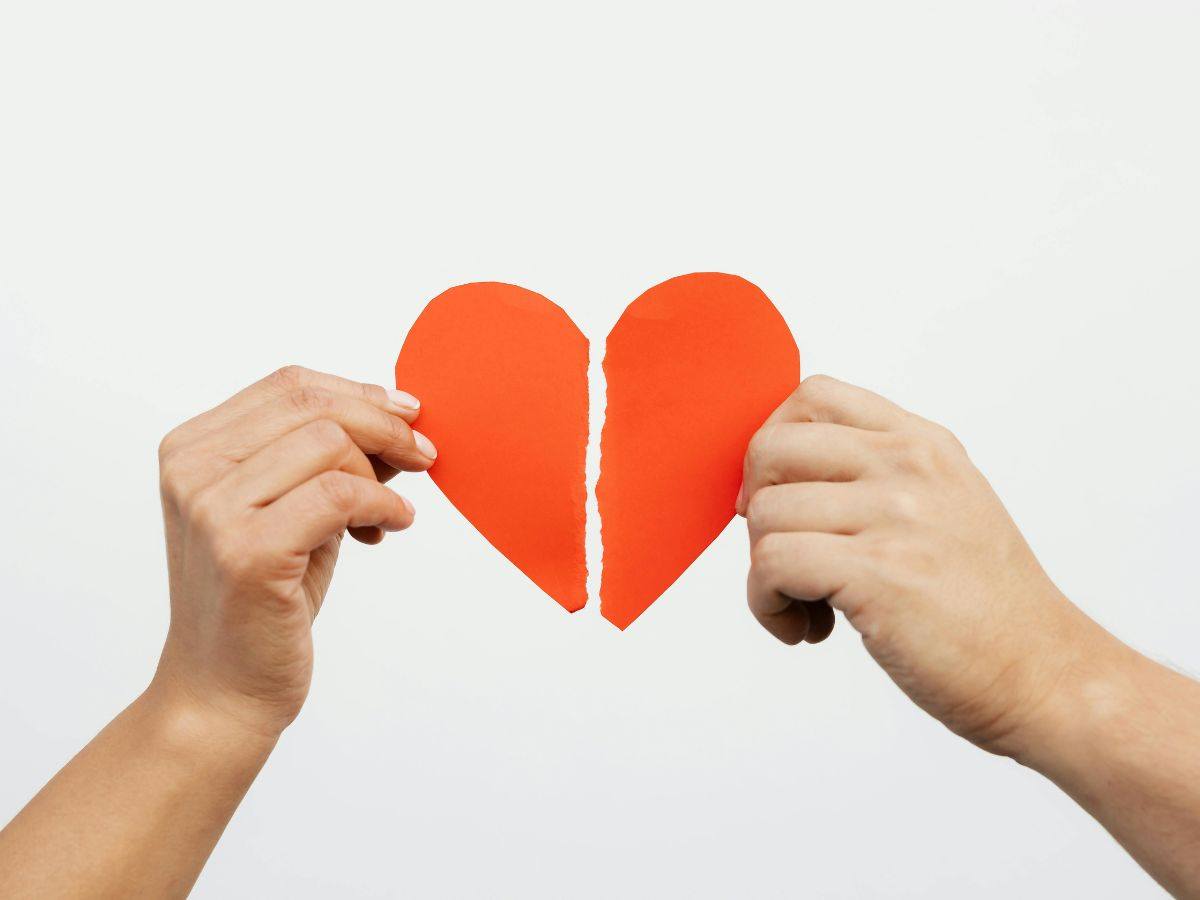 un cuore rotto di carta diviso da due mani