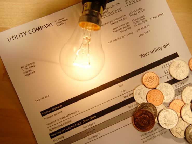 bolletta con delle monetina poggiate sopra e una piccola lampadina accesa