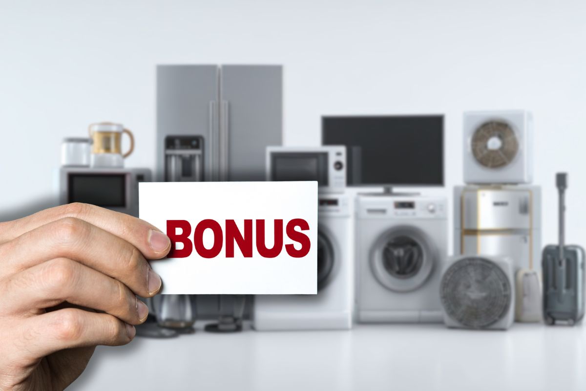 diversi elettrodomestici sullo sfondo e mano che tiene cartellino con scritta bonus