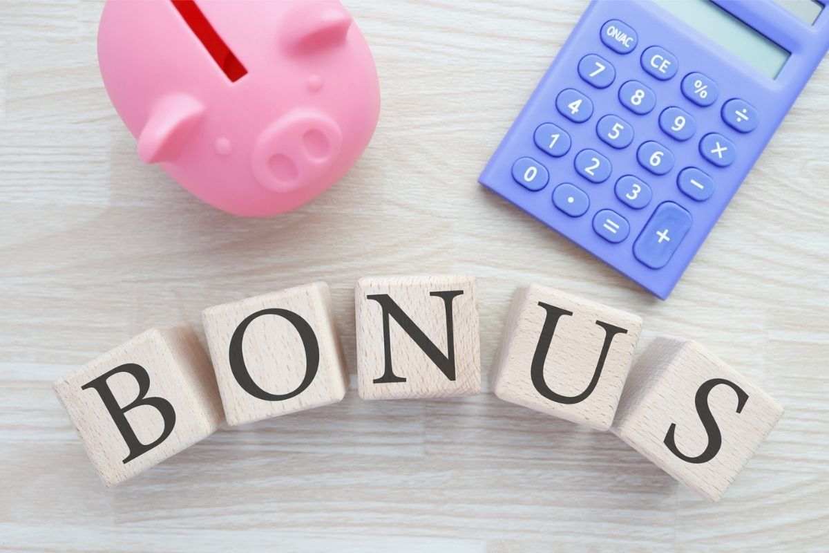 scritta bonus su cubi di legno, calcolatrice e porcellino a salvadanaio