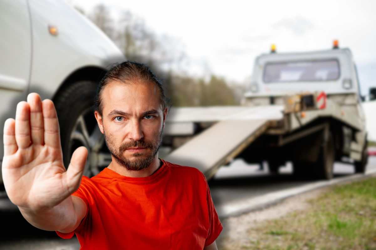 auto con carro attrezzi e uomo che fa stop con le mani