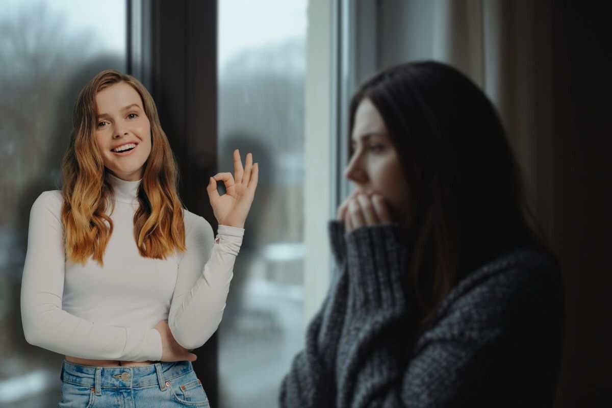 donna che sente freddo vicino la finestra di casa e un'altra sorridente che fa ok con le mani