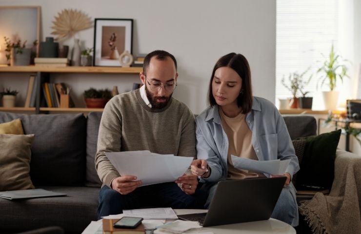 due persone che controllano delle carte con il pc aperto
