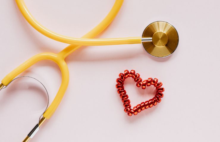 stetoscopio giallo e sagoma di cuore su sfondo rosa 