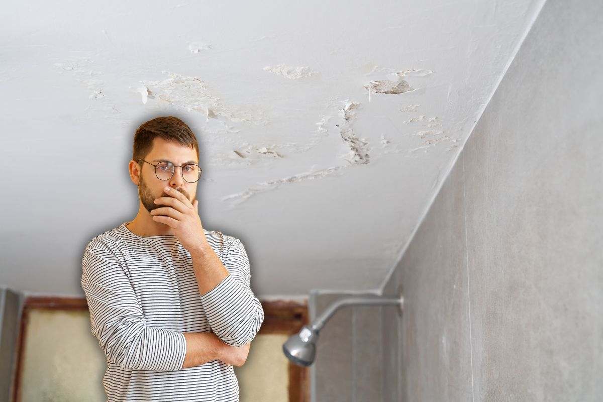 uomo pensieroso in primo piano e un soffitto con una macchia d'umidità