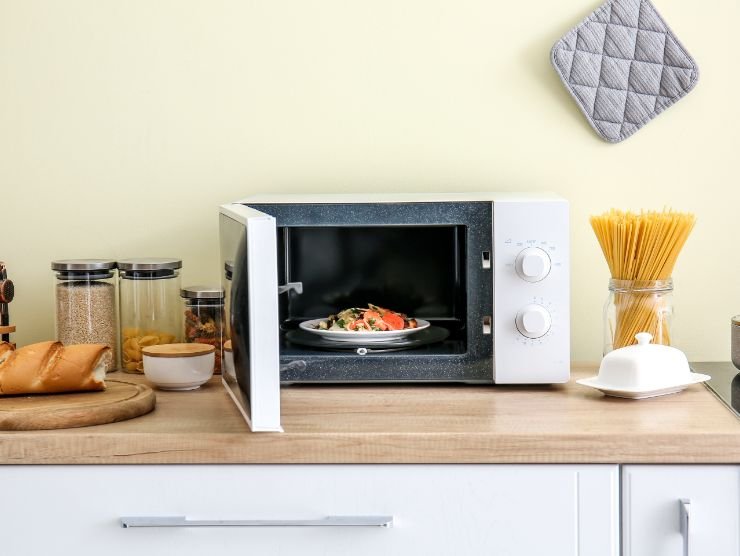 microonde aperto con un piatto di cibo 