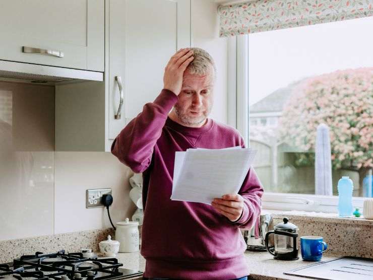 uomo all'interno di una cucina che legge una bolletta