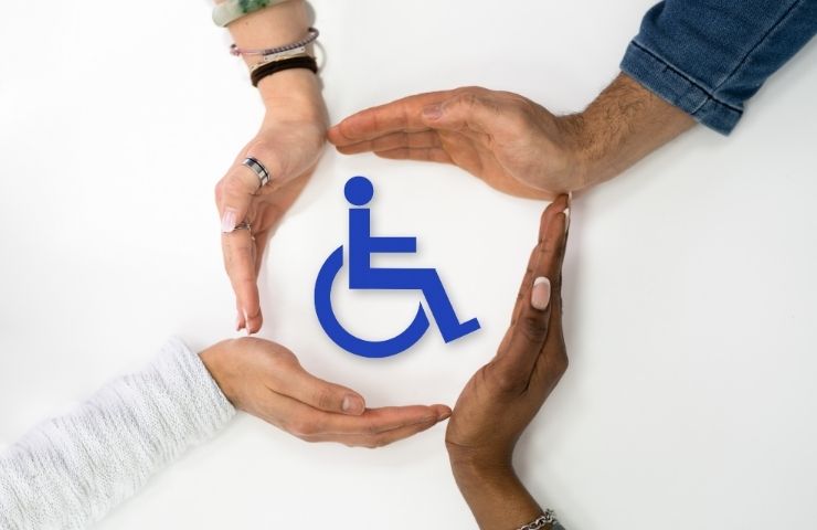 mani che si stringono intorno a sagoma di uomo su sedia a rotelle