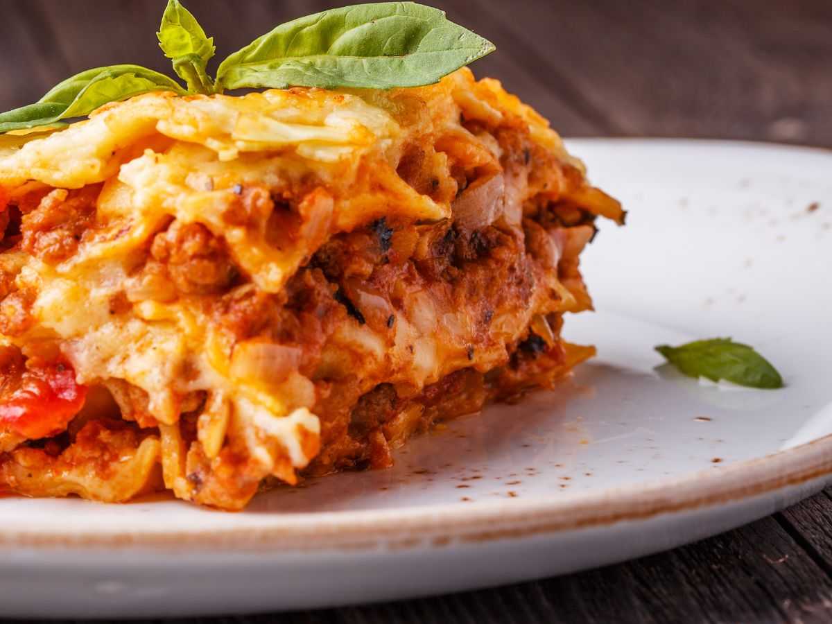 una porzione di lasagna con basilico fresco