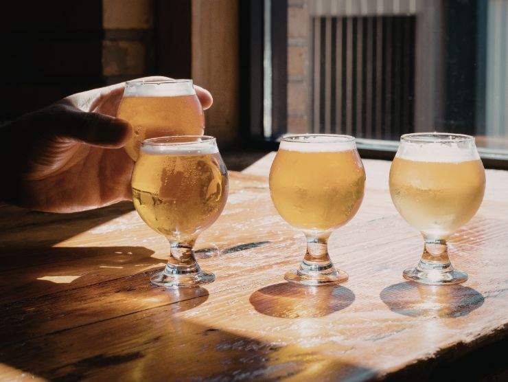 mano che mantiene un bicchiere di birra sistemato accanto ad altri boccali