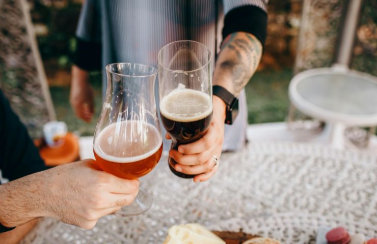 persone che brindano con birra in bicchiere
