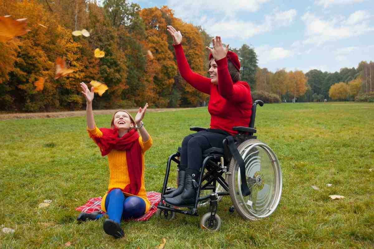persona disabile su sedia a rotelle e un'altra sorridente che le sta vicino