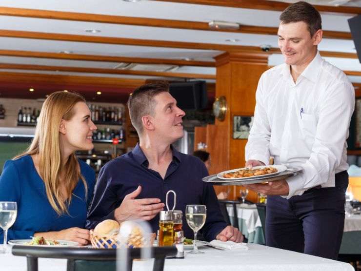 cameriere al ristornate che serve coppia