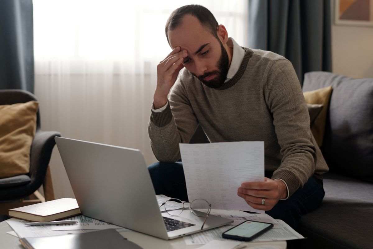 uomo che controlla al pc con carte in mano 