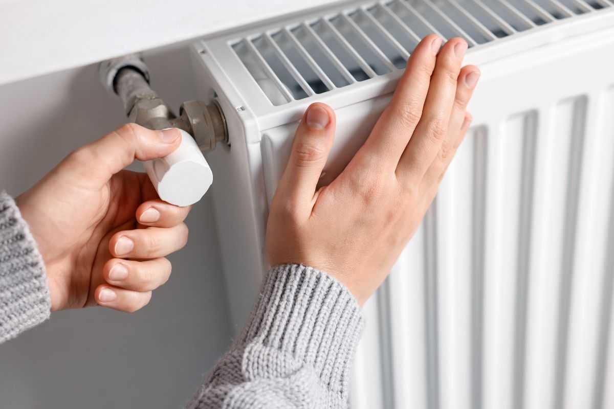 donna che imposta temperatura dei termosifoni e con una mano li tocca