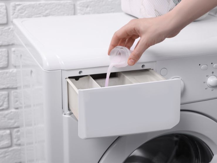 persona che versa del detersivo liquido nel cassetto della lavatrice