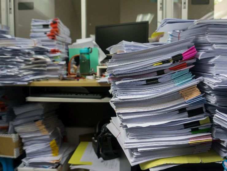 scrivania piena di faldoni di carte