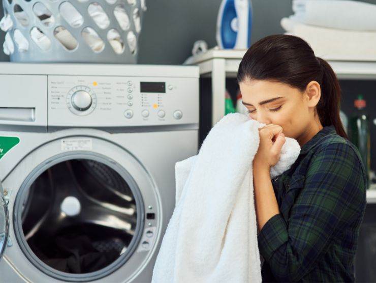 donna che annusa asciugamano appena uscito dalla lavatrice